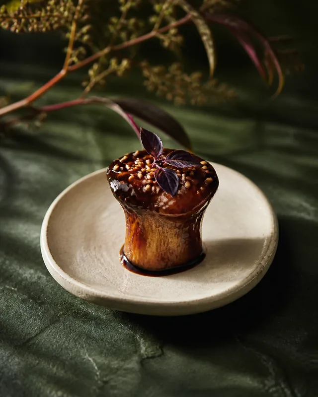 A lacquered mushroom tamarind bite with sesame and purple basil