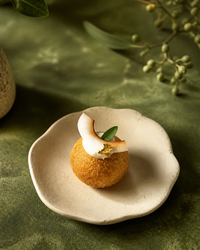A golden sweet potato coconut bite with lime leaf and coconut cream